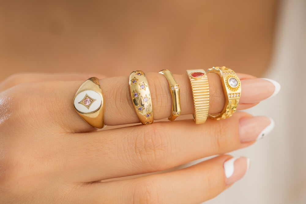 Woman's hand with various gold ring styles and designs.